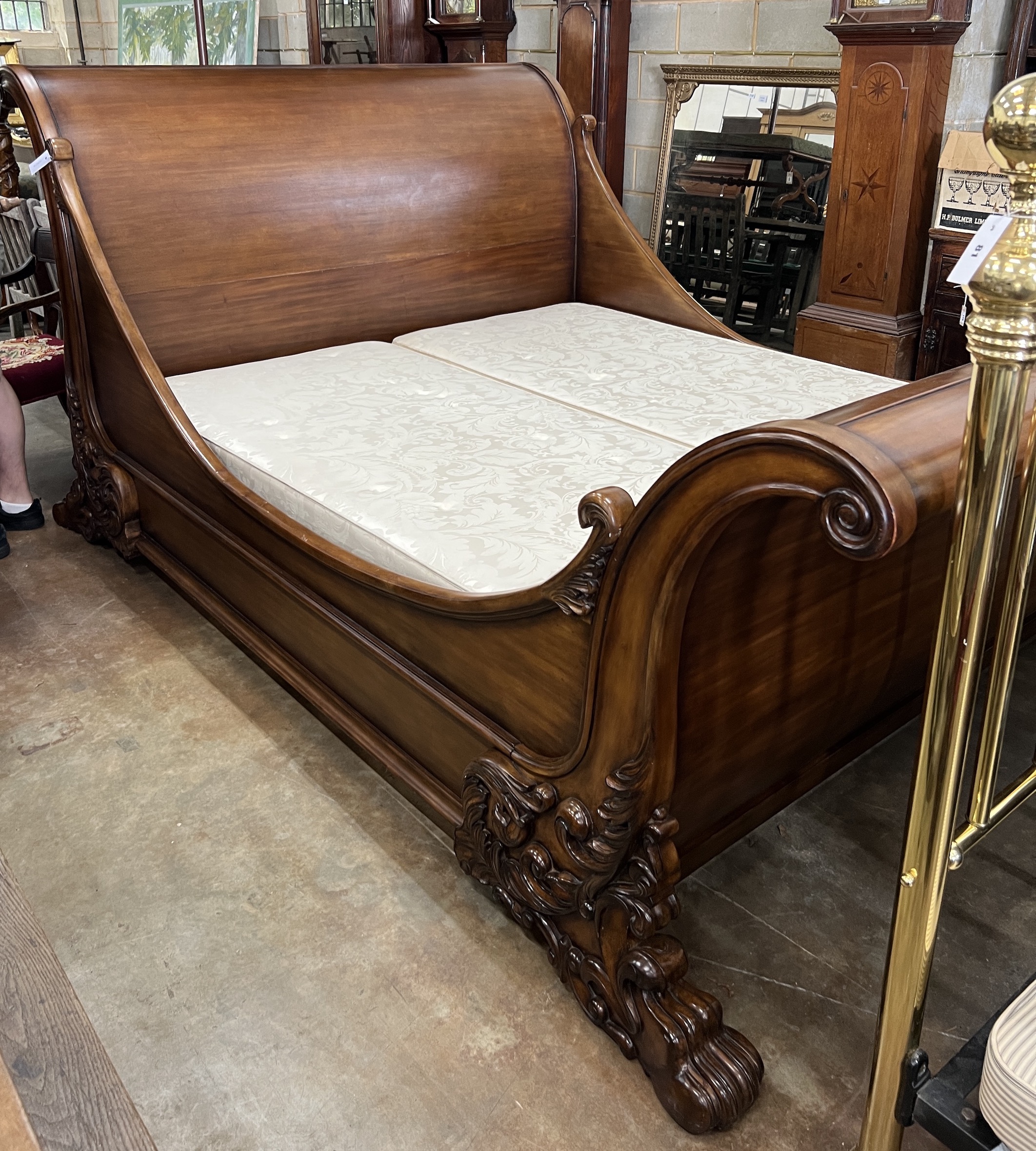 A good mahogany Superking sleigh bed by And So To Bed, London. Handmade copy of the Brodsworth bed, at Brodsworth Hall, South Yorkshire, with carved Lion's feet and scrollwork ends, with a Sienna veneer and hand-polished